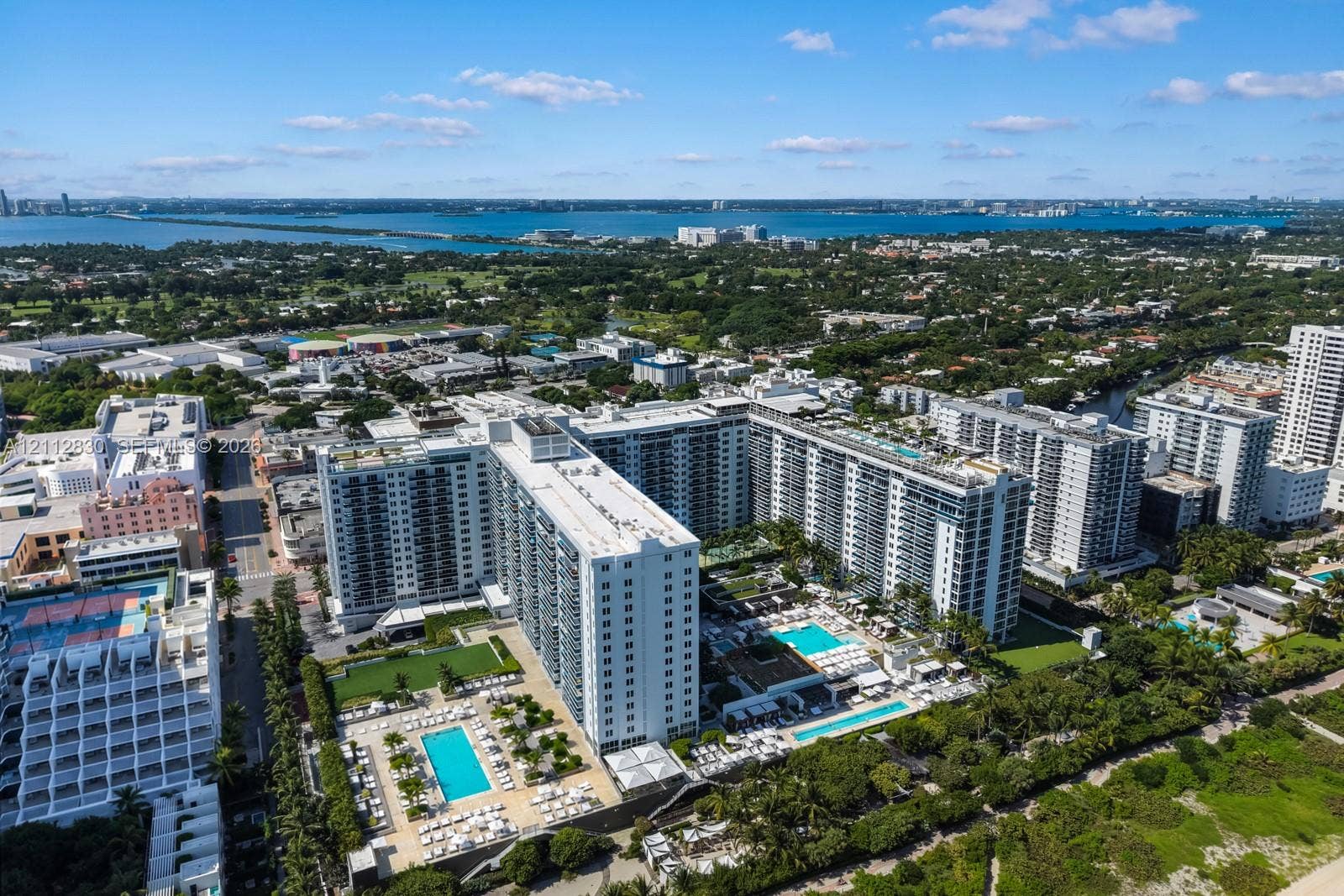 Aerial perspective featuring multiple high-rise structures, landscaped grounds, and multiple outdoor swimming pools