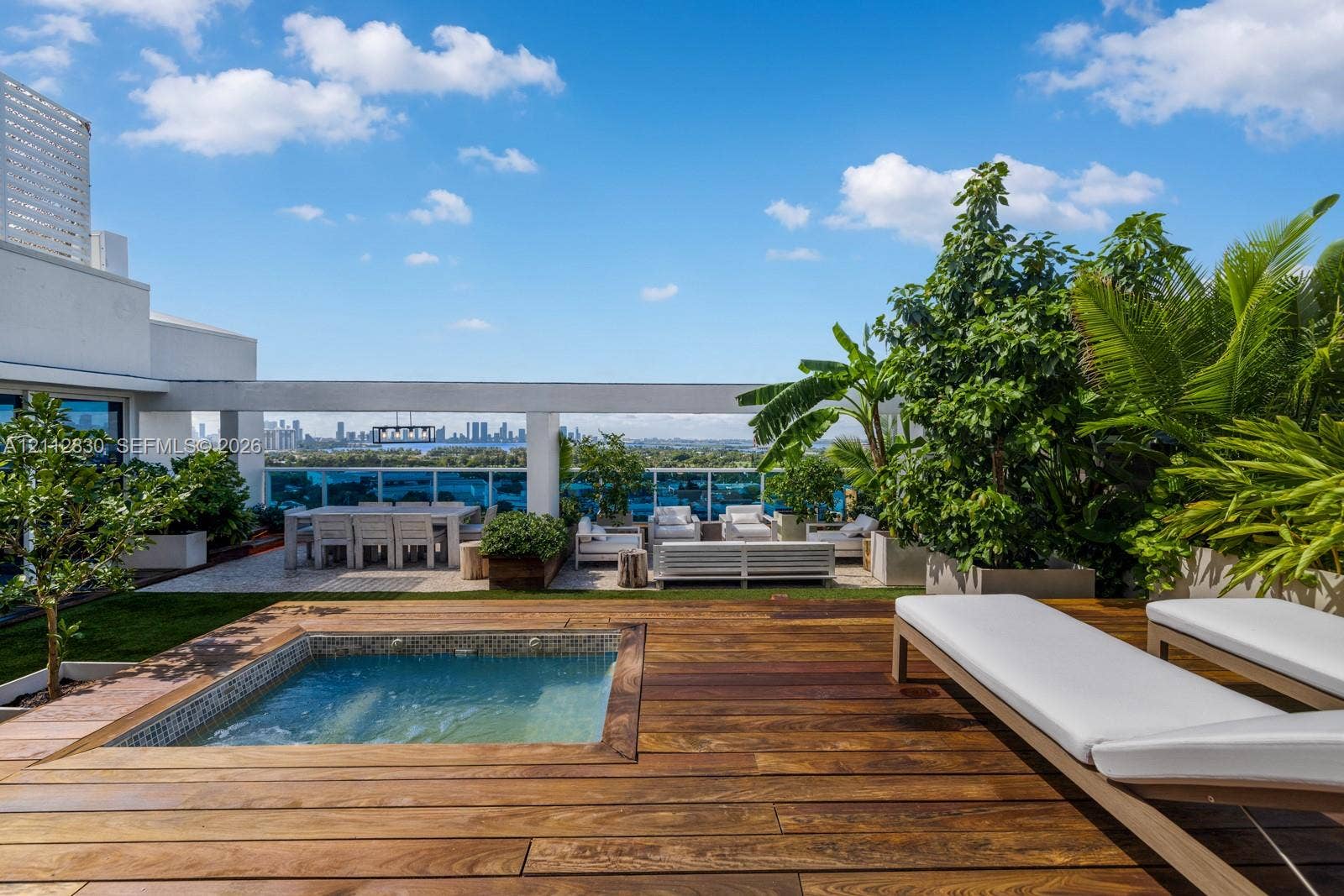 Rooftop terrace featuring wood-finish decking, an integrated in-ground spa, glass perimeter railing, and concrete planter boxes