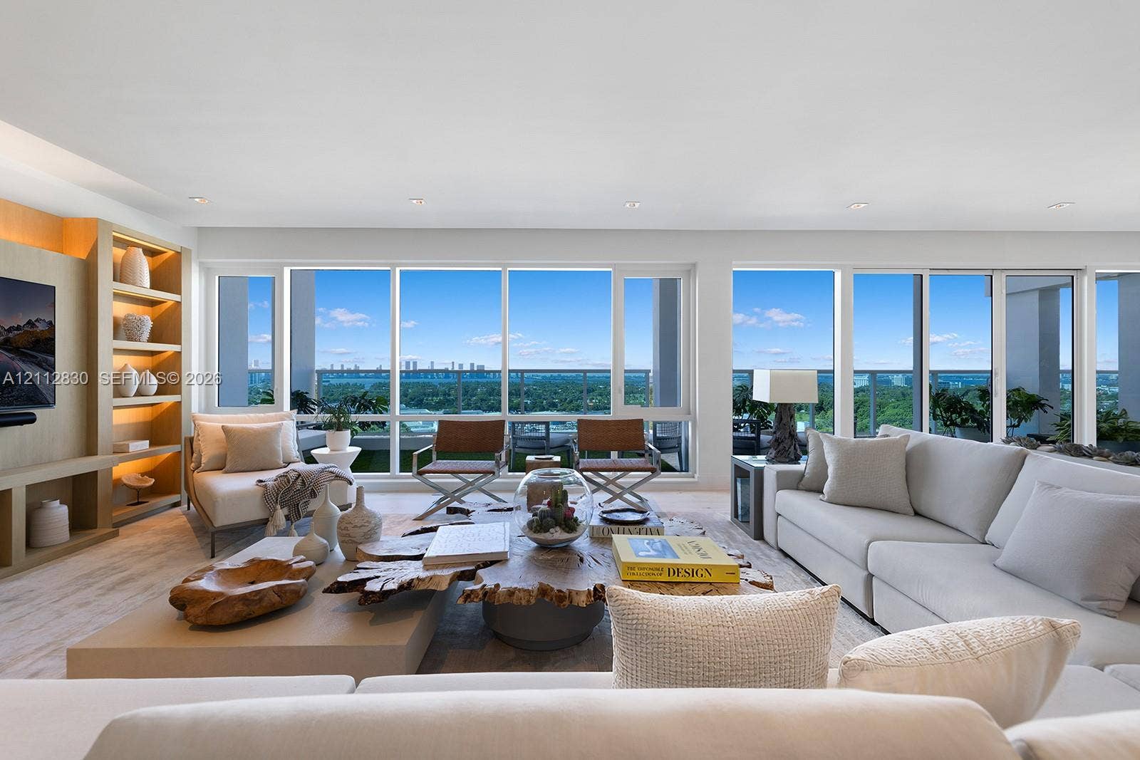 Living area featuring expansive floor-to-ceiling windows, integrated wall cabinetry with recessed shelving, and wood-finish flooring