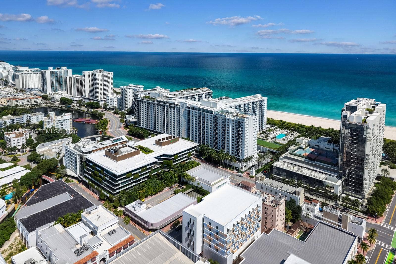 Aerial perspective of a coastal residential district featuring direct oceanfront proximity, sandy beach access, high-rise architecture, and expansive water coverage
