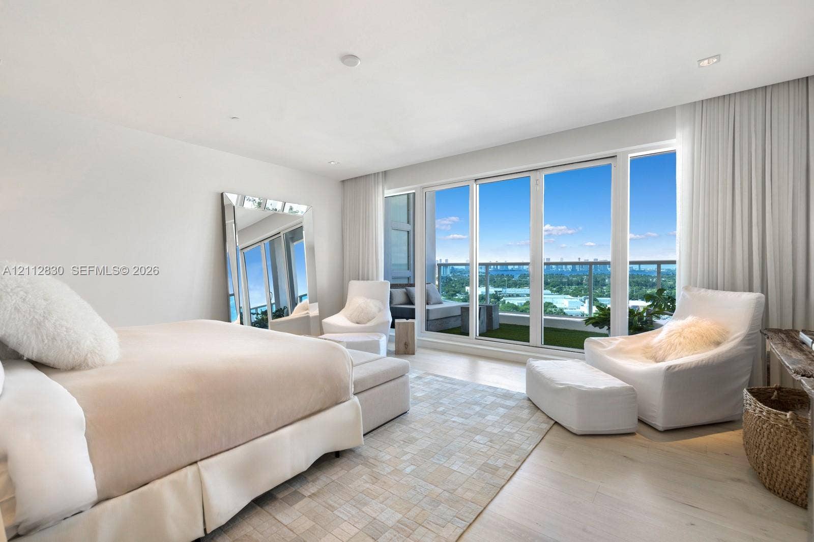 Floor-to-ceiling glass sliding doors, private balcony with metal railing, recessed ceiling lighting, and light-toned wood-finish flooring