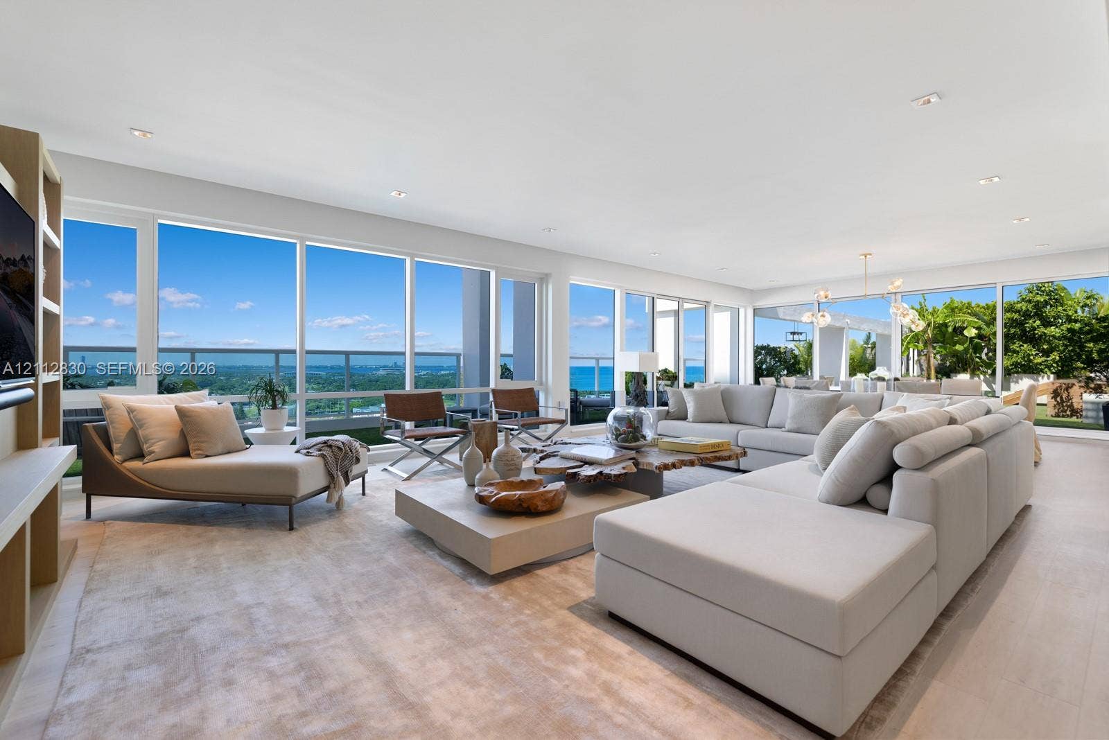 Expansive living space featuring floor-to-ceiling glass windows, wood-finish flooring, recessed lighting, and a built-in media shelving unit