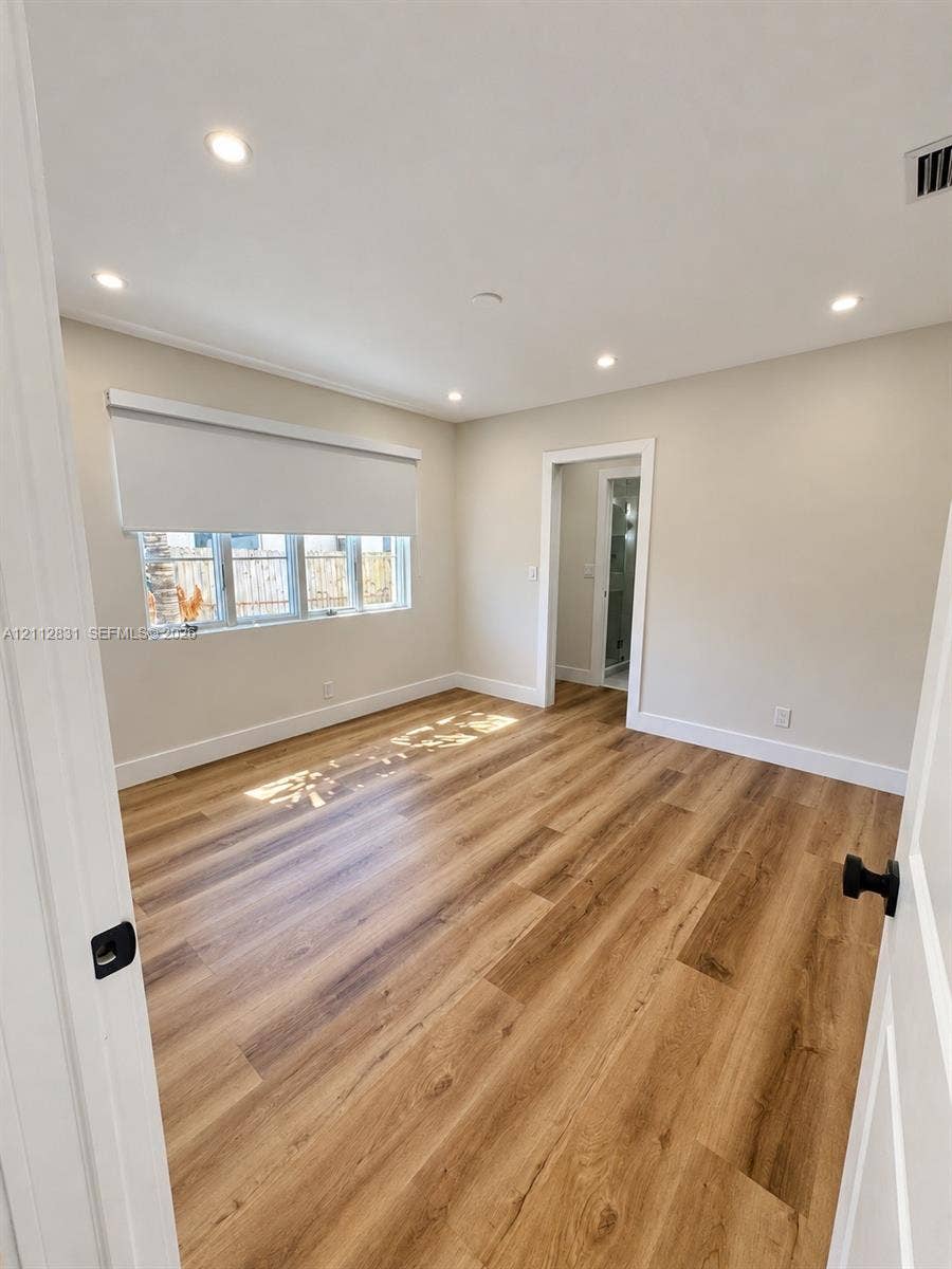 Room featuring wood-finish flooring, recessed lighting, neutral wall paint, and windows with integrated roller shades