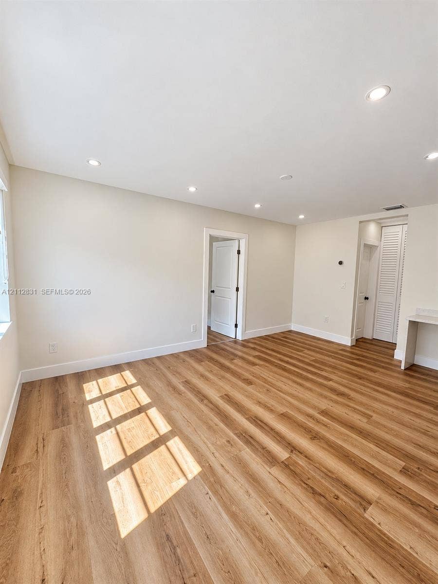 Wood-finish flooring, recessed lighting, neutral wall paint, and multi-panel interior doors