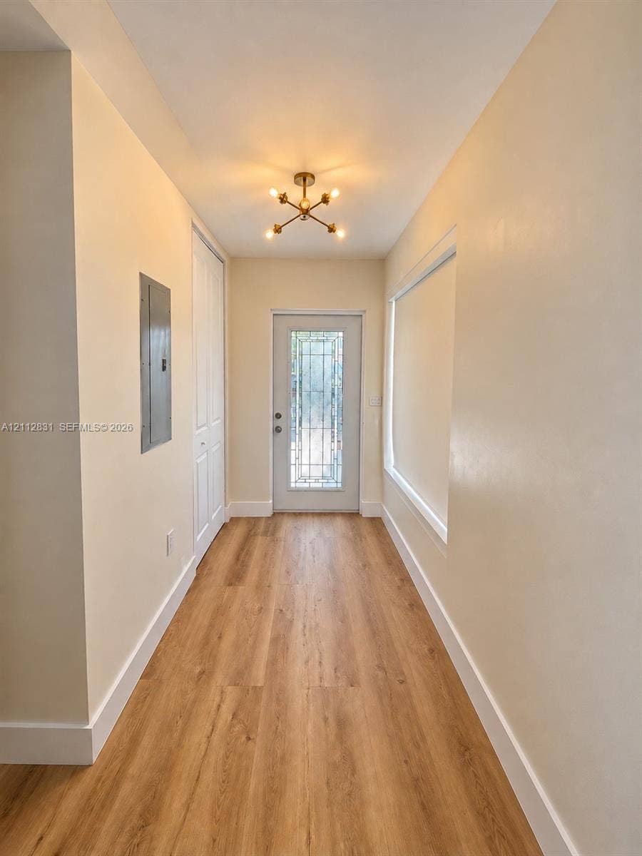 Entryway featuring wood-finish flooring, a multi-pane glass insert door, a modern sputnik-style flush-mount light fixture, and a built-in closet with paneled doors