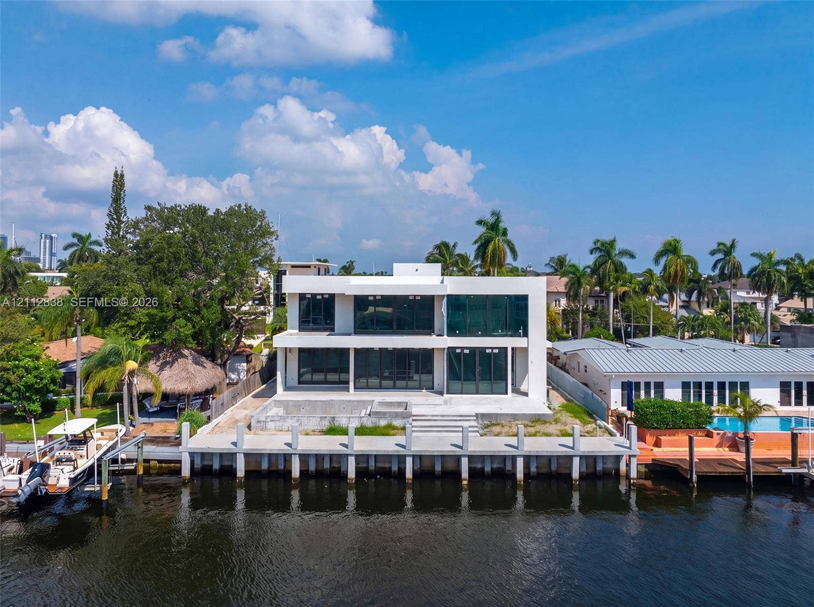 Modern two-story waterfront residence featuring floor-to-ceiling windows, a concrete bulkhead, and a private dock