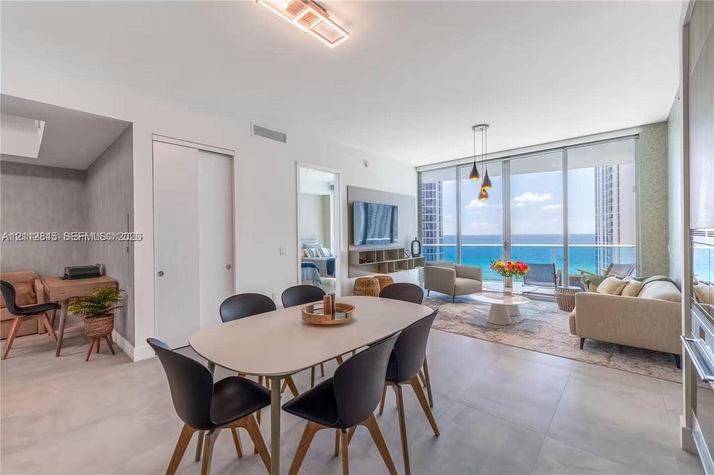 17550 Collins Avenue, #1202, Sunny Isles Beach, Sunny Isles Beach, FL 33160 Open-concept interior featuring large-format tile flooring, floor-to-ceiling glass walls, and a balcony with an ocean backdrop