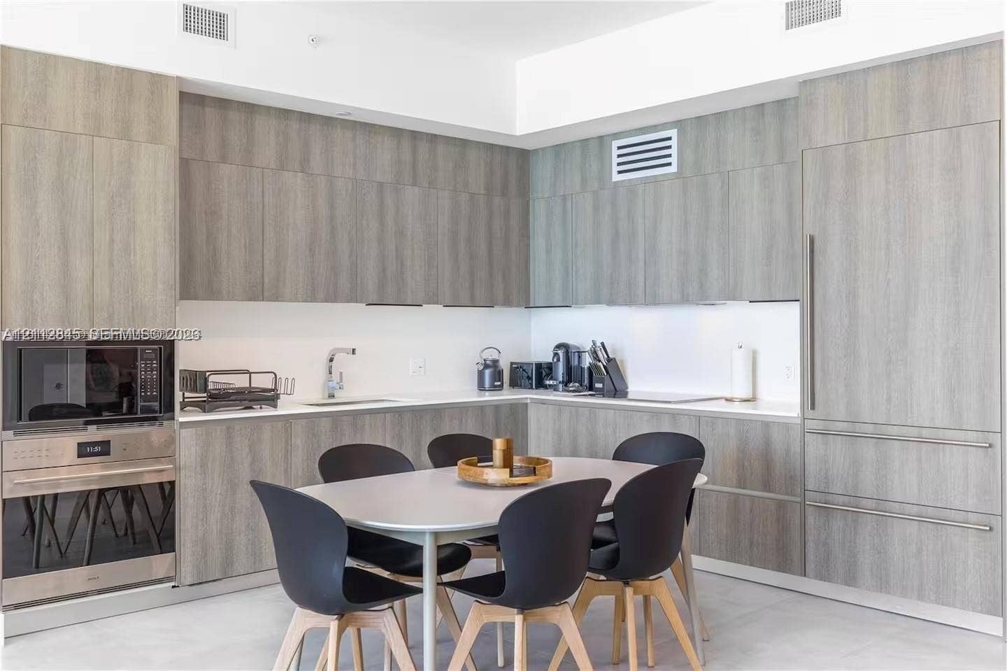 17550 Collins Avenue, #1202, Sunny Isles Beach, Sunny Isles Beach, FL 33160 Kitchen featuring flat-panel wood-finish cabinetry, integrated refrigerator, built-in stainless steel microwave and wall oven, and light-toned solid surface countertops