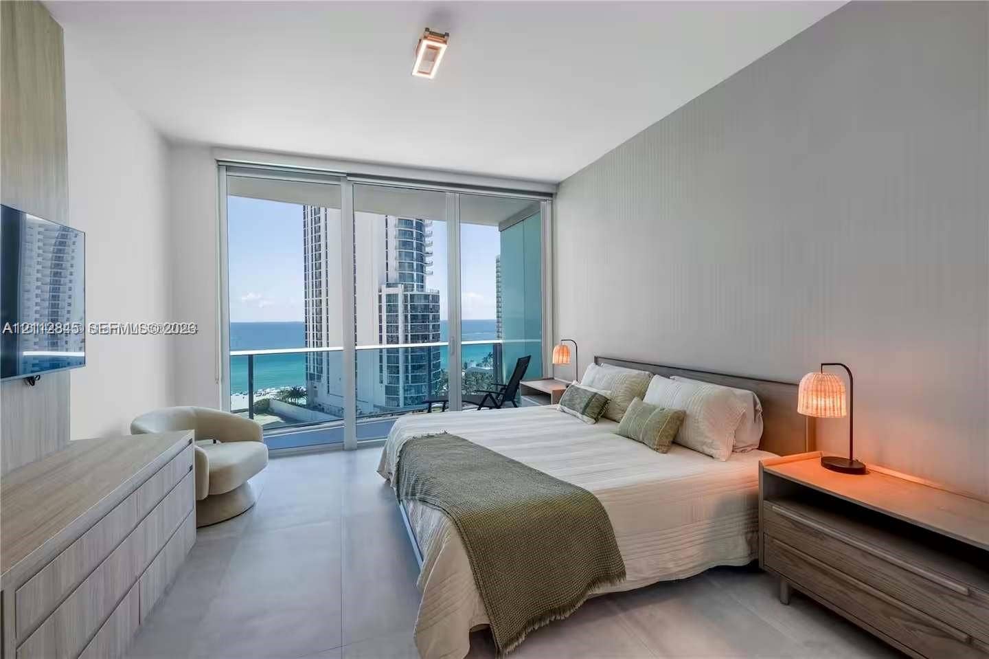 17550 Collins Avenue, #1202, Sunny Isles Beach, Sunny Isles Beach, FL 33160 Floor-to-ceiling glass sliding doors, large-format tile flooring, built-in wall paneling, and an integrated balcony with glass railing