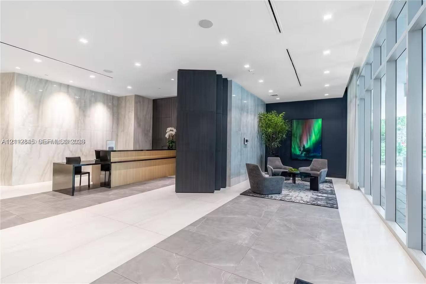 17550 Collins Avenue, #1202, Sunny Isles Beach, Sunny Isles Beach, FL 33160 Lobby area featuring large-format tile flooring, stone-clad accent walls, floor-to-ceiling windows, recessed lighting, and a custom built-in reception desk