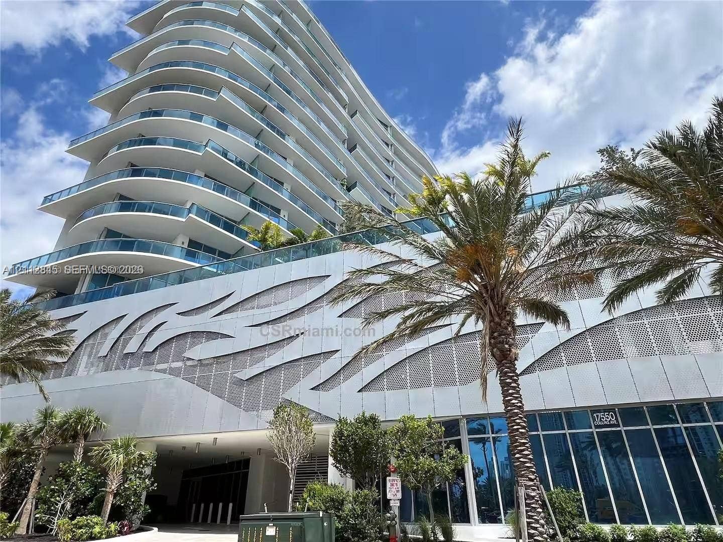 17550 Collins Avenue, #1202, Sunny Isles Beach, Sunny Isles Beach, FL 33160 High-rise architectural exterior featuring tiered glass balconies, metallic geometric facade paneling, floor-to-ceiling glass windows, and mature palm landscaping