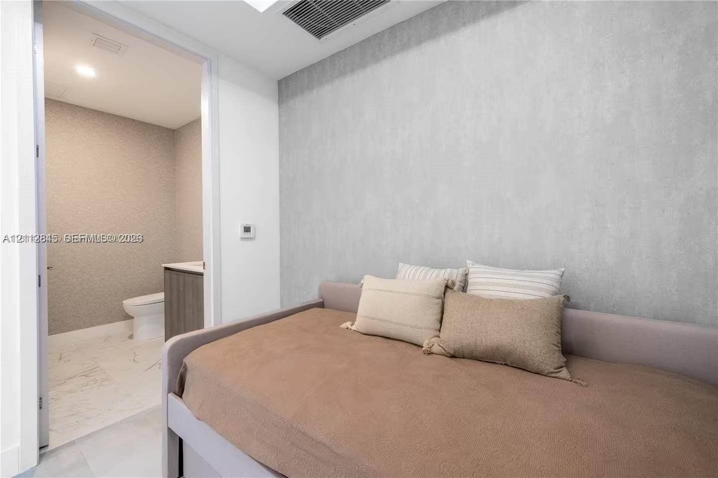 17550 Collins Avenue, #1202, Sunny Isles Beach, Sunny Isles Beach, FL 33160 Textured accent wall, neutral interior palette, and recessed ceiling lighting, with an entry to a bathroom featuring stone-finish floor tiling and a floating vanity