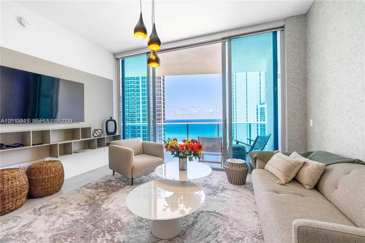 17550 Collins Avenue, #1202, Sunny Isles Beach, Sunny Isles Beach, FL 33160 Floor-to-ceiling glass doors, custom built-in cabinetry, modern pendant lighting, textured wall finish, and a glass-paneled balcony