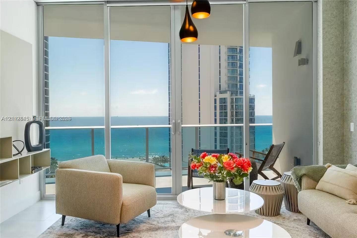 17550 Collins Avenue, #1202, Sunny Isles Beach, Sunny Isles Beach, FL 33160 Floor-to-ceiling glass sliding doors, private balcony with metal railing, pendant light fixture with tiered shades, and custom built-in shelving