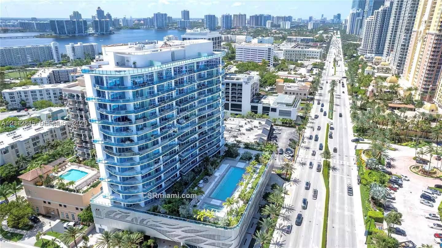 17550 Collins Avenue, #1202, Sunny Isles Beach, Sunny Isles Beach, FL 33160 High-rise residential building featuring a glass facade, expansive wrap-around balconies, a structured podium base with decorative relief, and a recreational deck containing a swimming pool