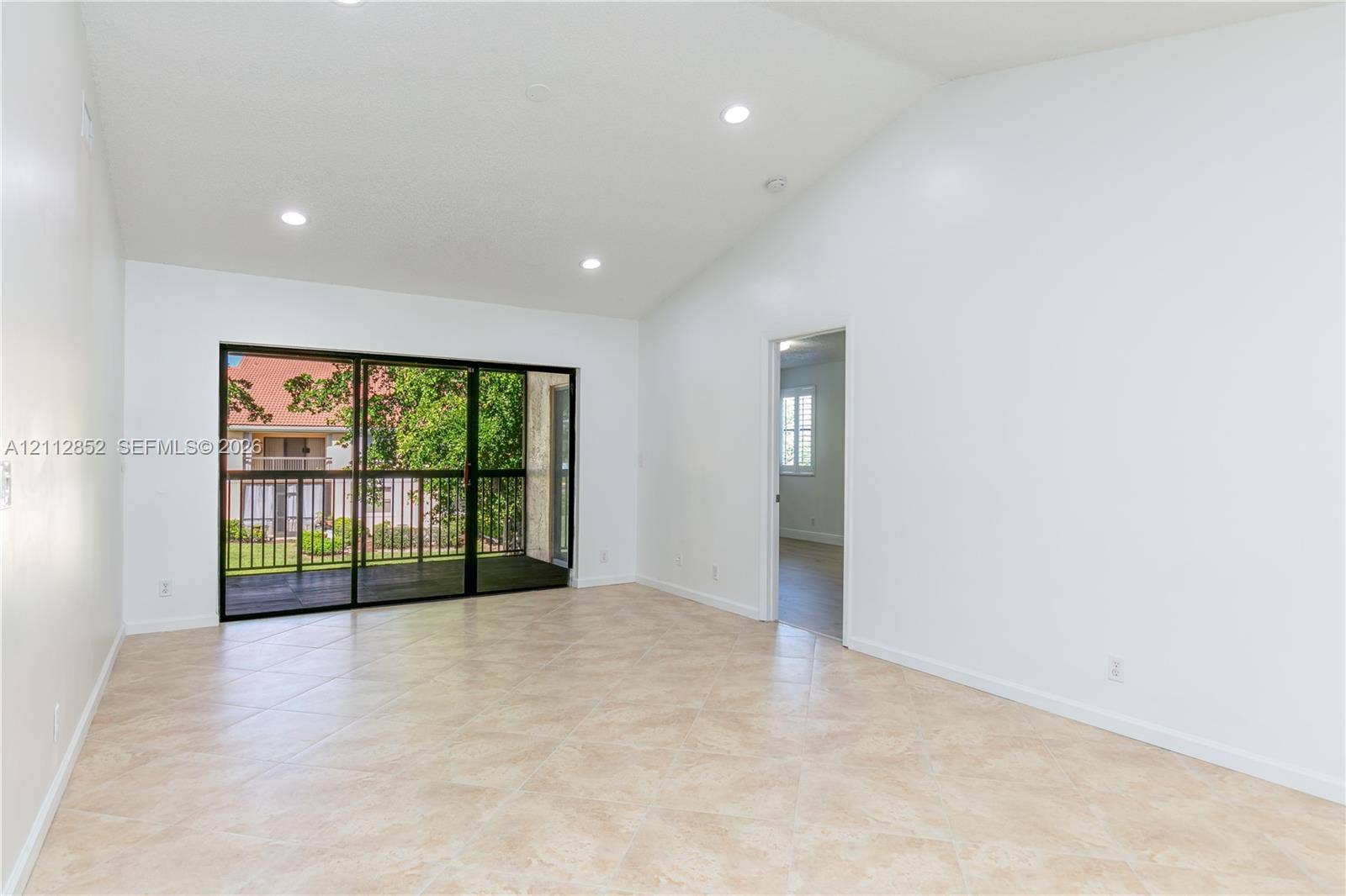 5741 Riverside Drive, #205A5, Coral Springs, Coral Springs, FL 33067 Vaulted ceilings, recessed lighting, tile flooring, and large sliding glass doors providing access to a screened balcony