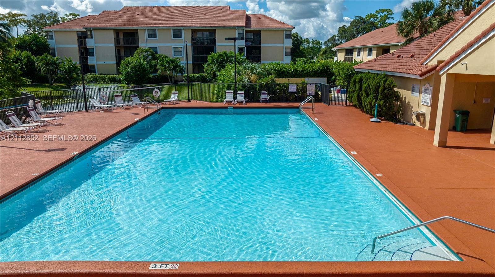 5741 Riverside Drive, #205A5, Coral Springs, Coral Springs, FL 33067 In-ground swimming pool with surrounding deck, metal perimeter fencing, and structured water feature