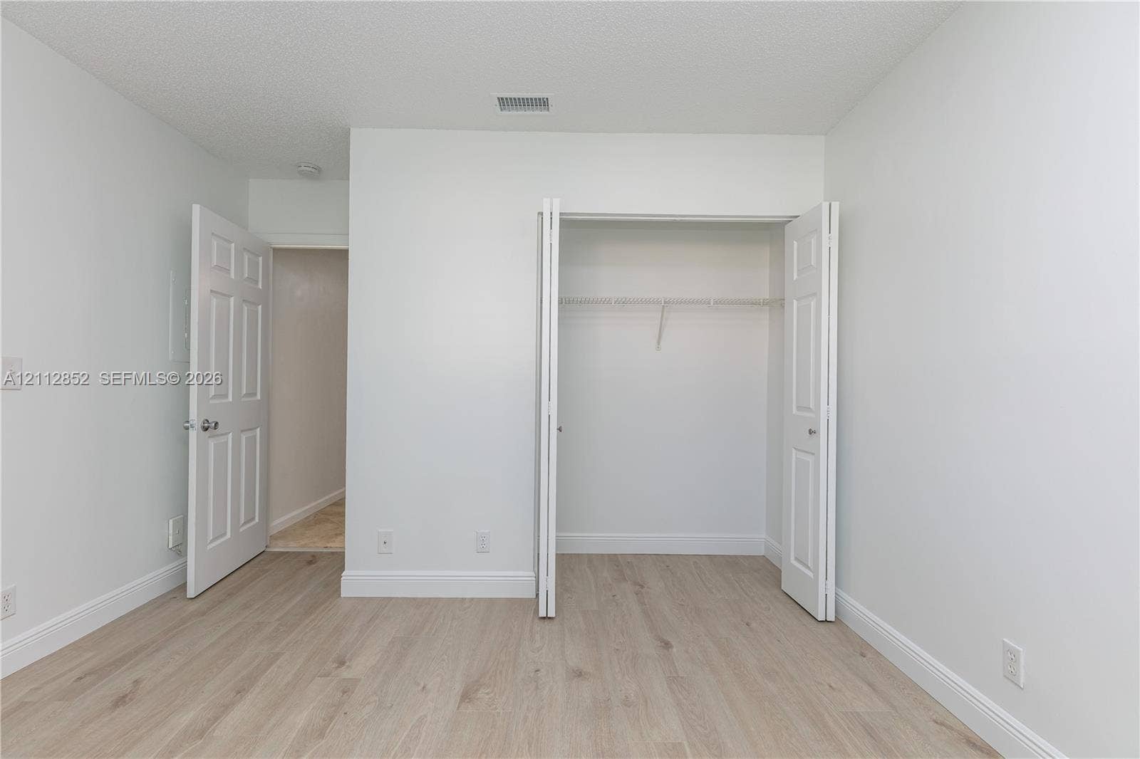 5741 Riverside Drive, #205A5, Coral Springs, Coral Springs, FL 33067 Room featuring wood-finish flooring, white walls, and a closet with bifold doors and built-in shelving