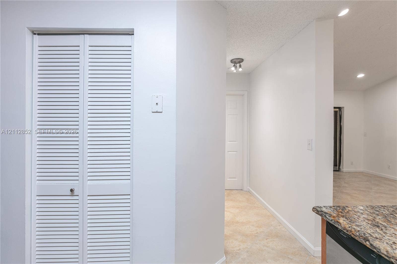 5741 Riverside Drive, #205A5, Coral Springs, Coral Springs, FL 33067 White louvered closet doors, neutral stone-finish tile flooring, multi-directional ceiling lighting, and a multi-toned stone countertop