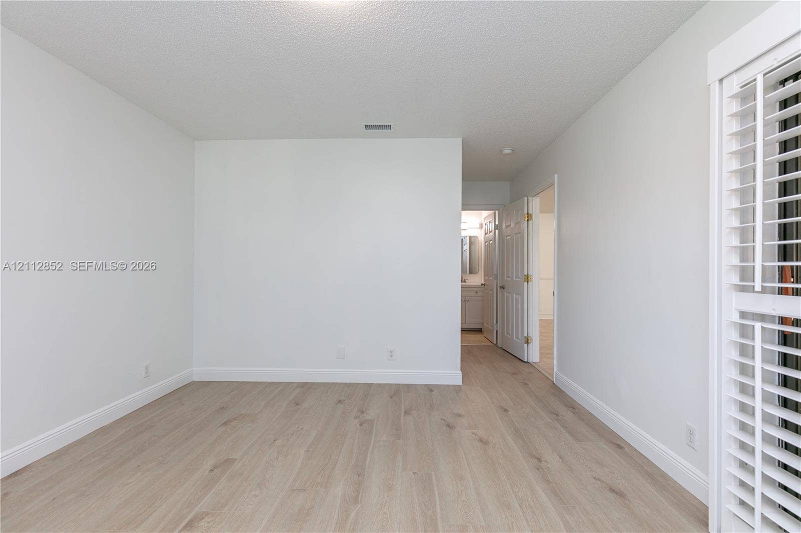 5741 Riverside Drive, #205A5, Coral Springs, Coral Springs, FL 33067 Room featuring light-toned wood-finish flooring, white walls, and interior louvered shutters