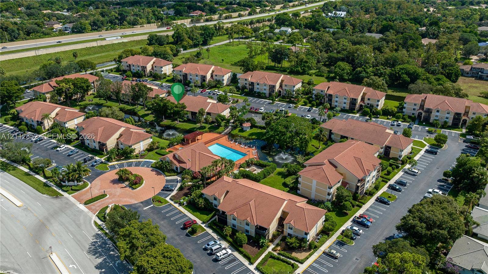 5741 Riverside Drive, #205A5, Coral Springs, Coral Springs, FL 33067 Aerial perspective of a multi-building residential community featuring tile roofing, a central swimming pool, landscaped grounds, and dedicated surface parking