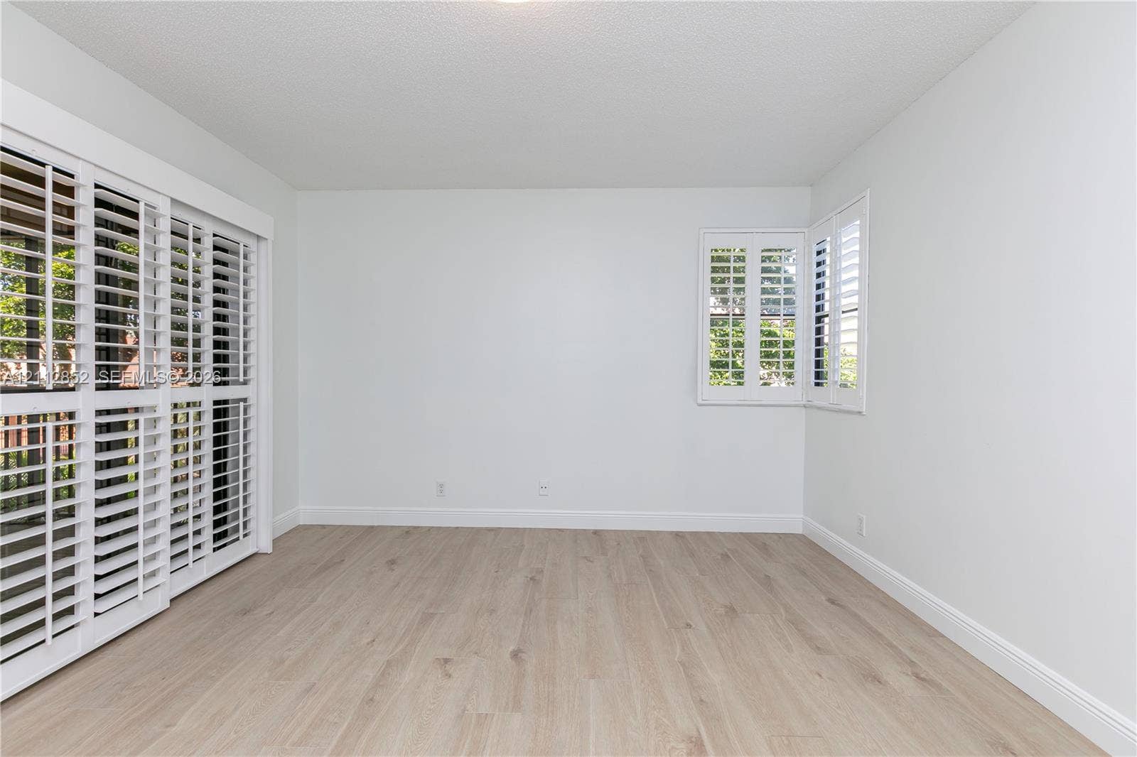 5741 Riverside Drive, #205A5, Coral Springs, Coral Springs, FL 33067 Neutral interior featuring wood-finish flooring, sliding glass doors, and white plantation shutters on windows