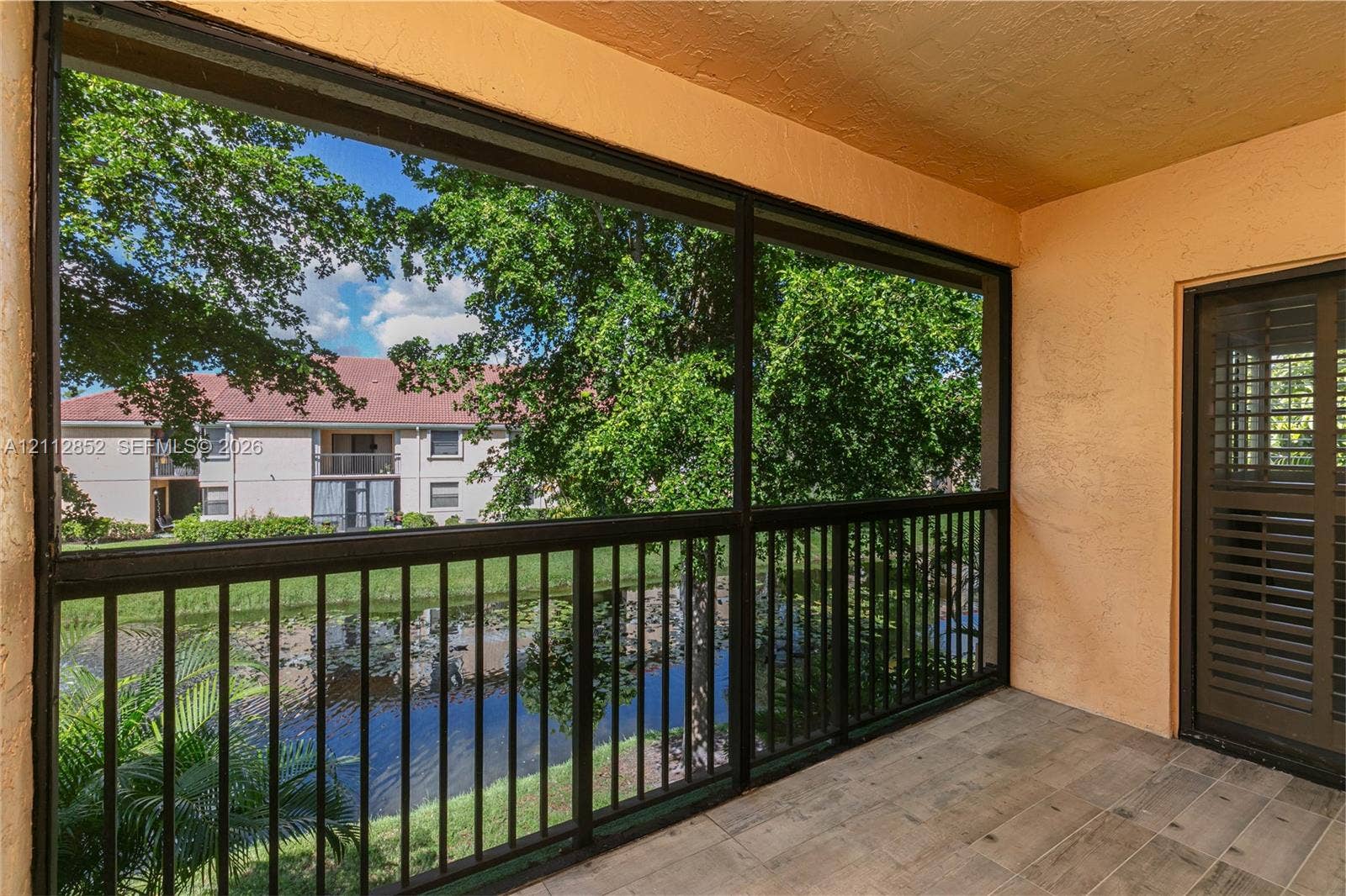 5741 Riverside Drive, #205A5, Coral Springs, Coral Springs, FL 33067 Screened-in balcony featuring wood-finish flooring, metal railing, and direct water exposure