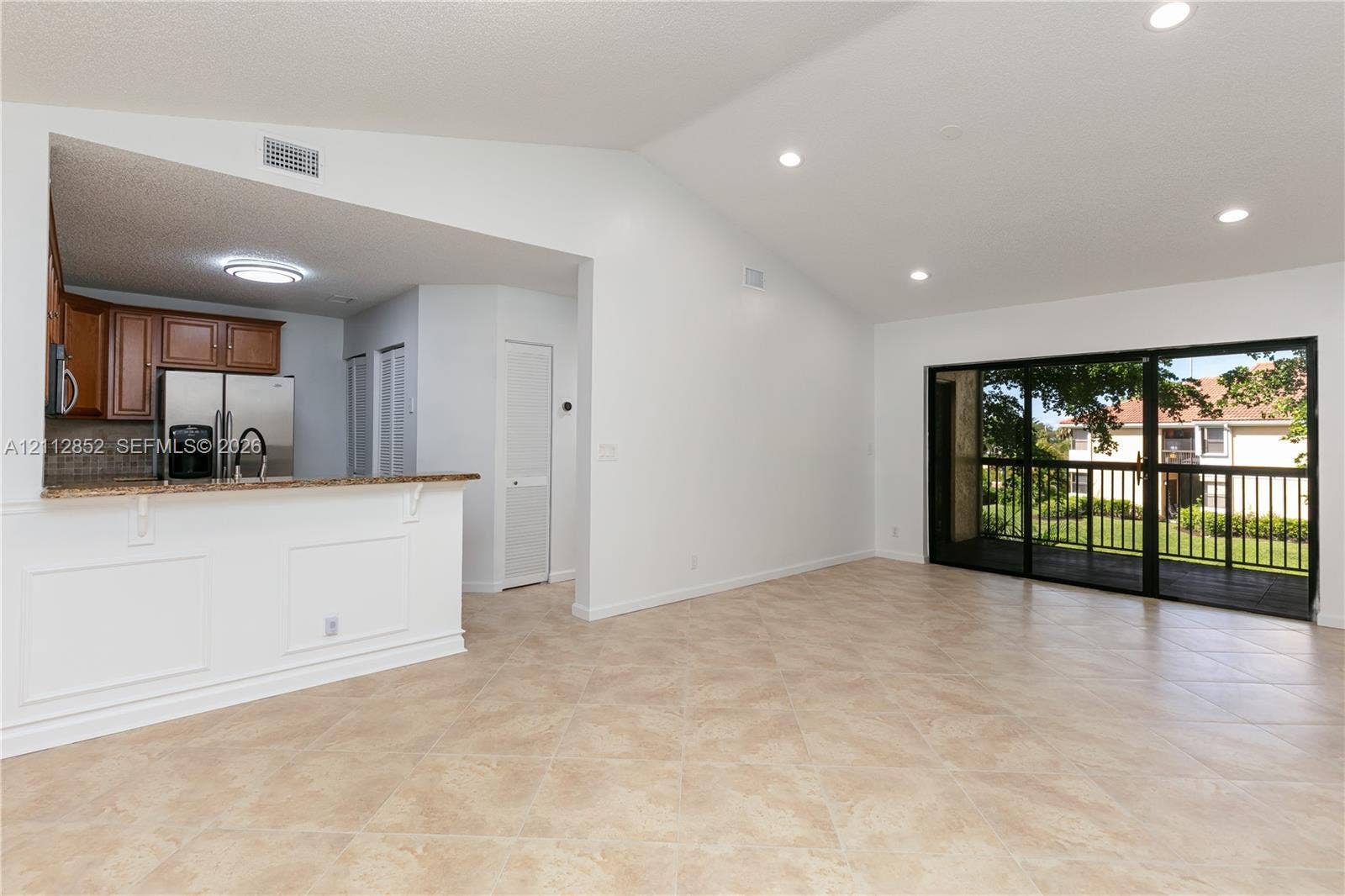 5741 Riverside Drive, #205A5, Coral Springs, Coral Springs, FL 33067 Vaulted ceilings, neutral tile flooring, recessed lighting, stone-surfaced breakfast bar, and large glass sliding doors providing exterior access