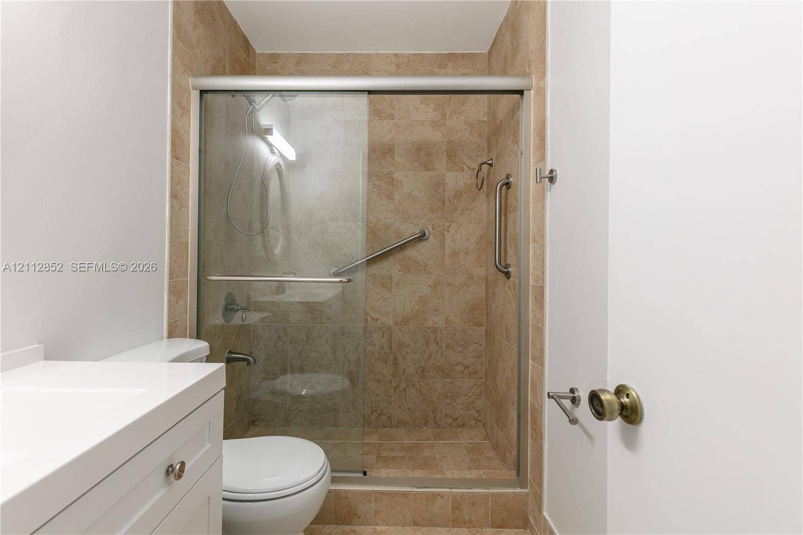 5741 Riverside Drive, #205A5, Coral Springs, Coral Springs, FL 33067 Walk-in shower featuring floor-to-ceiling tile surround, glass sliding door, integrated grab bars, and adjustable shower head