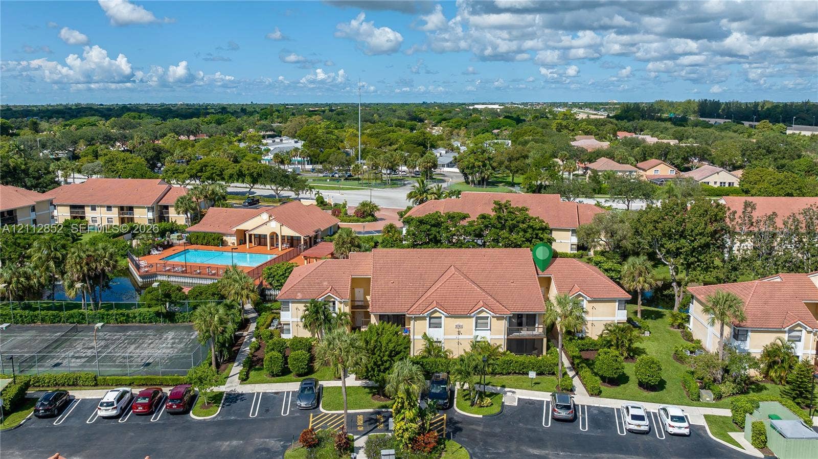 5741 Riverside Drive, #205A5, Coral Springs, Coral Springs, FL 33067 Aerial view of residential complex featuring a tile roof, paved parking area, landscaping, and community-accessible swimming pool and tennis court