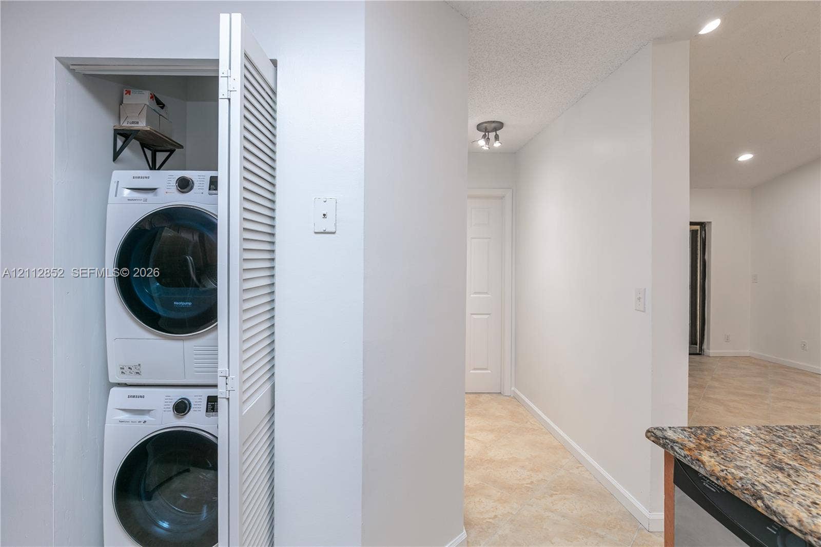 5741 Riverside Drive, #205A5, Coral Springs, Coral Springs, FL 33067 Stacked laundry unit featuring white appliances housed within a louvered-door closet, complemented by tile flooring and recessed lighting