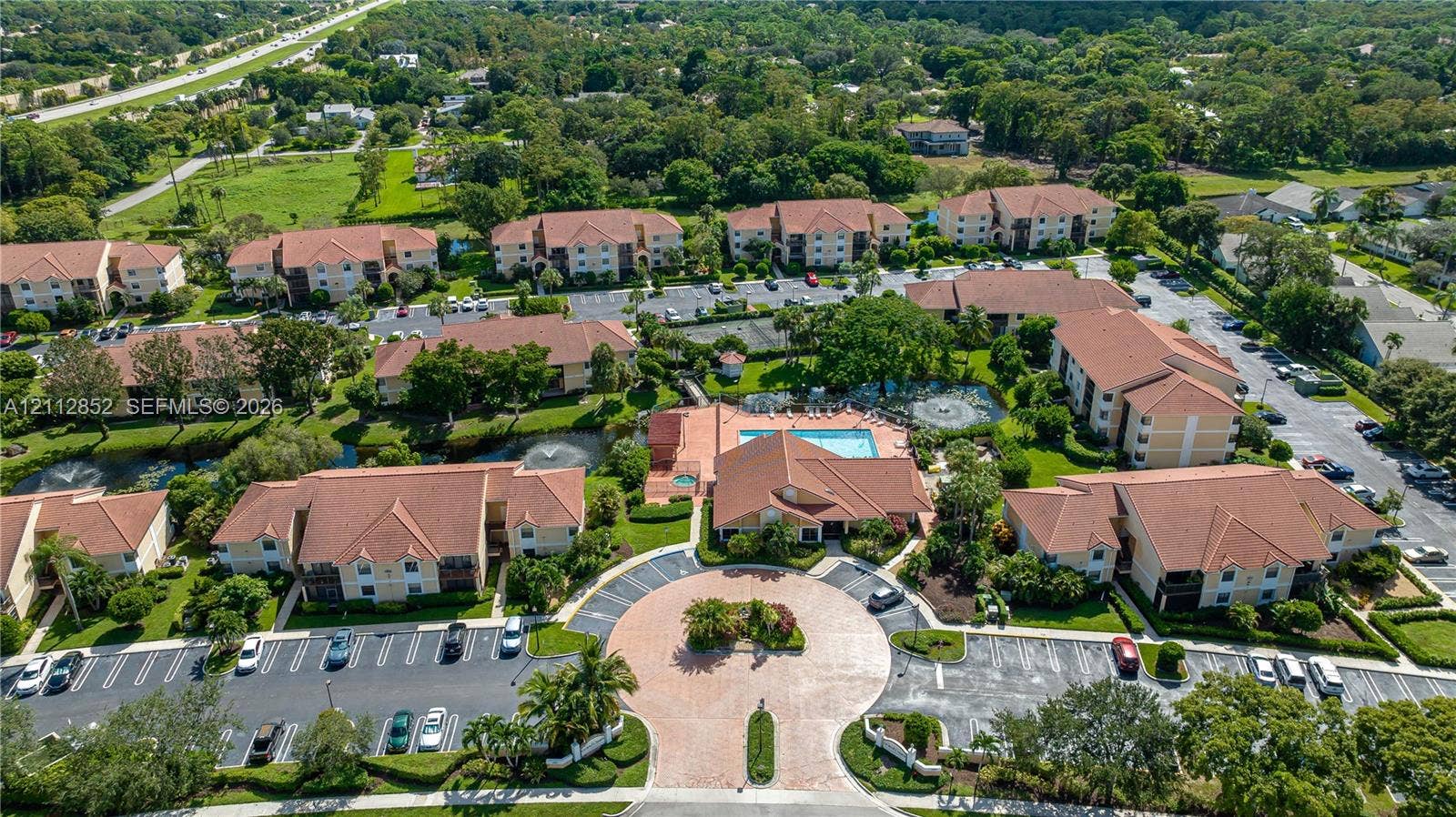 5741 Riverside Drive, #205A5, Coral Springs, Coral Springs, FL 33067 Multi-building residential complex featuring tile roofing, paved circular motor court, community swimming pool, and manicured landscaping