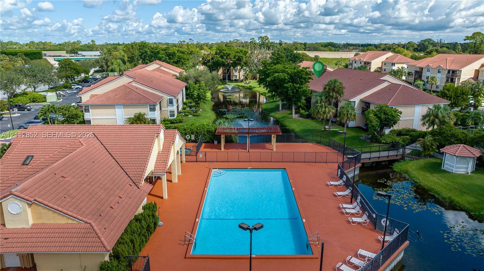 5741 Riverside Drive, #205A5, Coral Springs, Coral Springs, FL 33067 Community swimming pool with surrounding terrace, terracotta-style roof tiles, central water feature with fountain, covered pergola structure, and landscaped grounds
