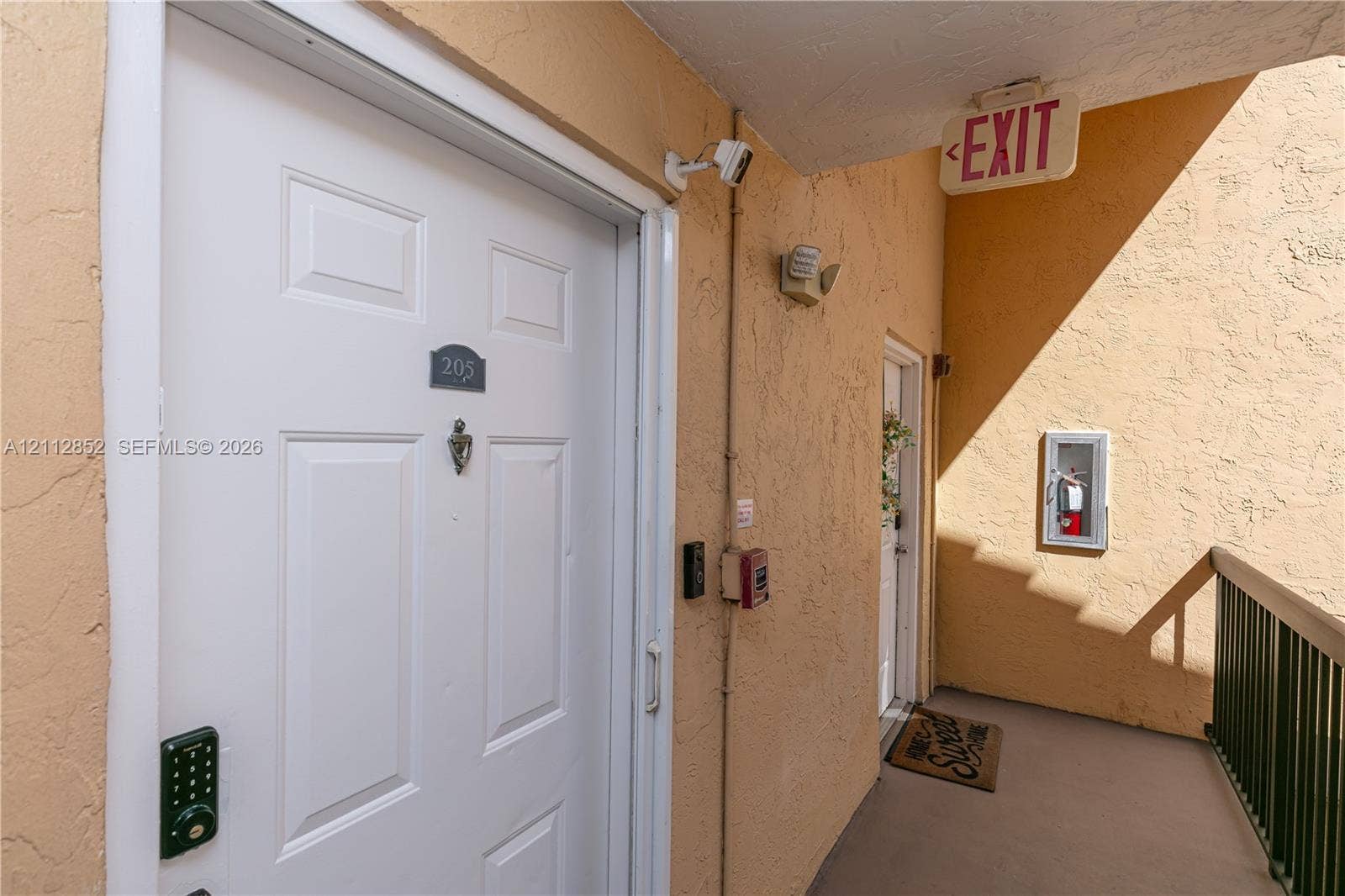5741 Riverside Drive, #205A5, Coral Springs, Coral Springs, FL 33067 Exterior entrance featuring a white panel door, metal door knocker, digital keypad entry system, and a surveillance camera