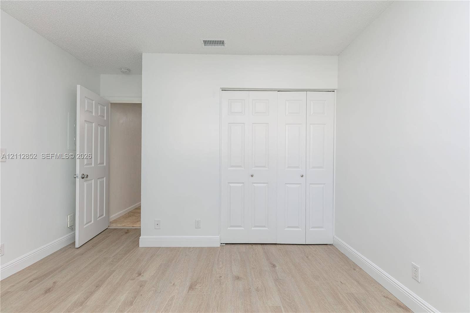 5741 Riverside Drive, #205A5, Coral Springs, Coral Springs, FL 33067 Room featuring neutral wall paint, wood-finish flooring, and a white bifold closet door
