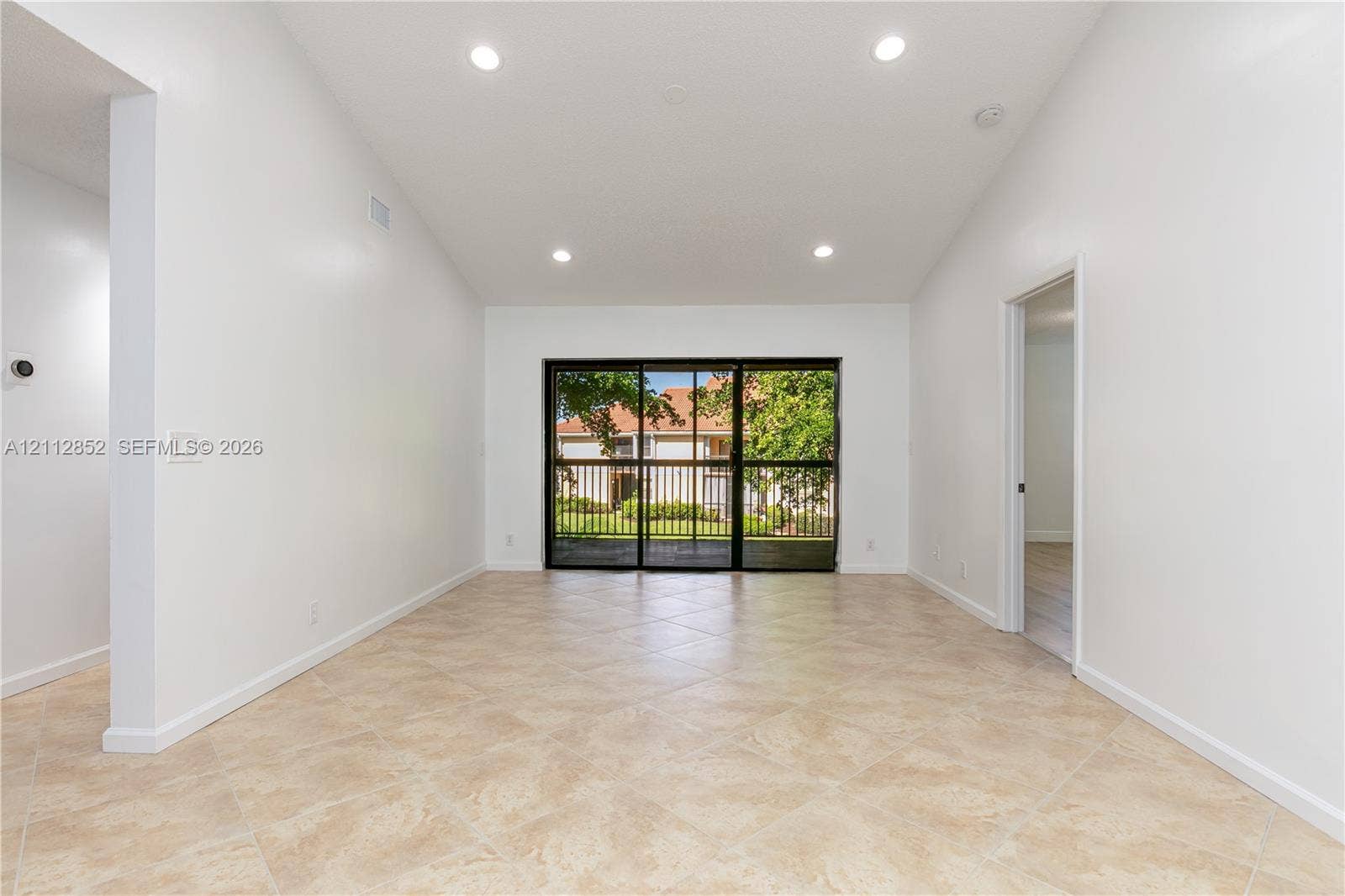 5741 Riverside Drive, #205A5, Coral Springs, Coral Springs, FL 33067 Vaulted ceilings, neutral tile flooring, recessed lighting, and large sliding glass doors featuring a black frame