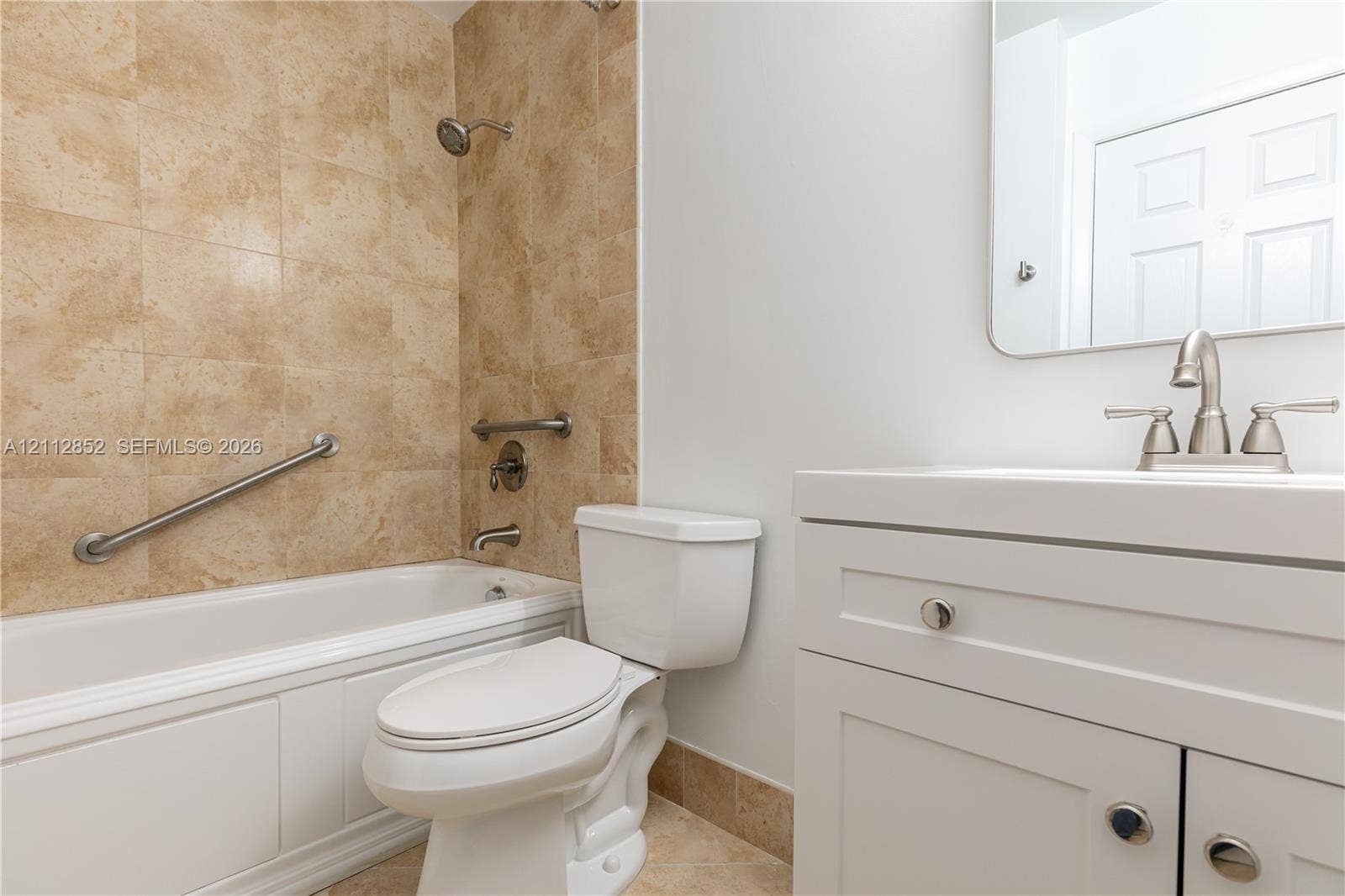 5741 Riverside Drive, #205A5, Coral Springs, Coral Springs, FL 33067 Bathroom featuring a white vanity cabinet with a integrated sink, polished metal faucet hardware, a tiled tub surround, and installed grab bars