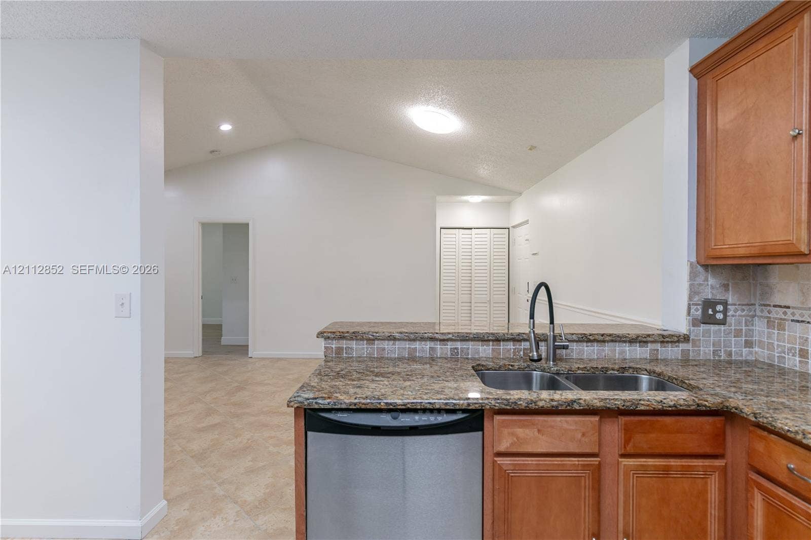 5741 Riverside Drive, #205A5, Coral Springs, Coral Springs, FL 33067 Kitchen featuring stone-finish countertops, tile backsplash, undermount double-basin sink, stainless steel dishwasher, and wooden cabinetry