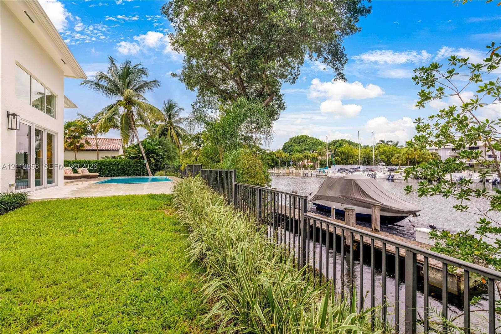 285 Las Brisas Court, Coral Gables, FL 33143 Waterfront property featuring a private boat dock, swimming pool, manicured lawn, and metal perimeter fencing