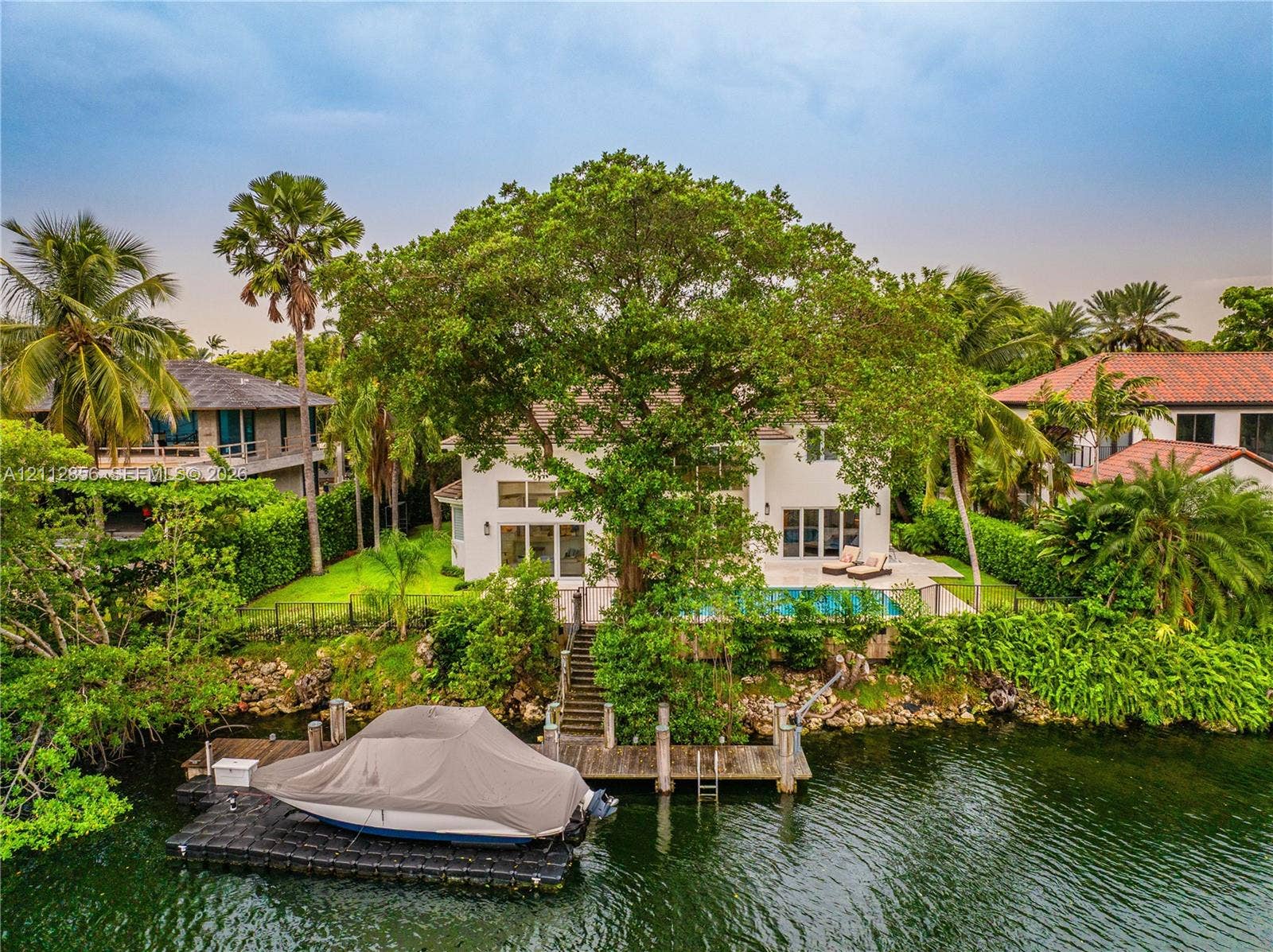 285 Las Brisas Court, Coral Gables, FL 33143 Waterfront property featuring a private boat dock, swimming pool, concrete patio, and mature trees
