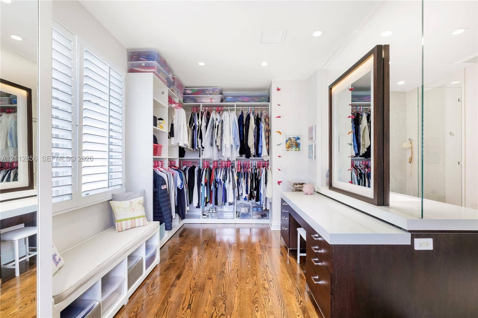 285 Las Brisas Court, Coral Gables, FL 33143 Custom dressing room featuring integrated floor-to-ceiling cabinetry, recessed lighting, wood-finish flooring, plantation shutters, and a built-in vanity with an illuminated mirror