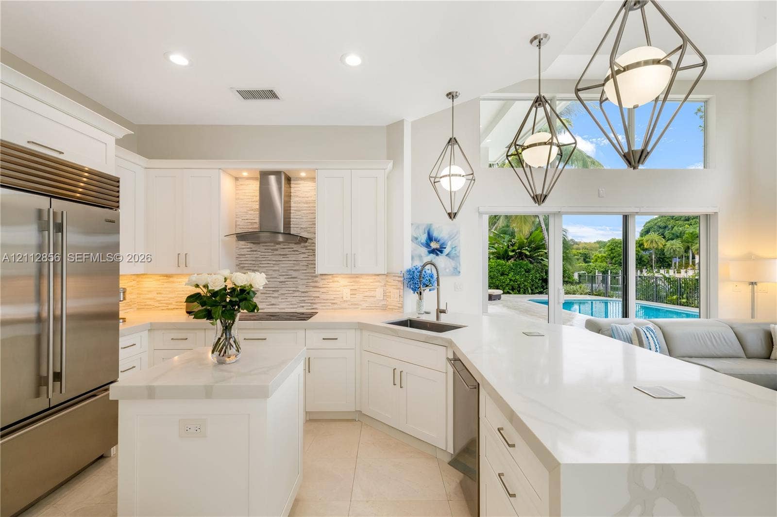 285 Las Brisas Court, Coral Gables, FL 33143 Kitchen featuring white cabinetry, quartz countertops, a stainless steel refrigerator, tile backsplash, and geometric pendant lighting