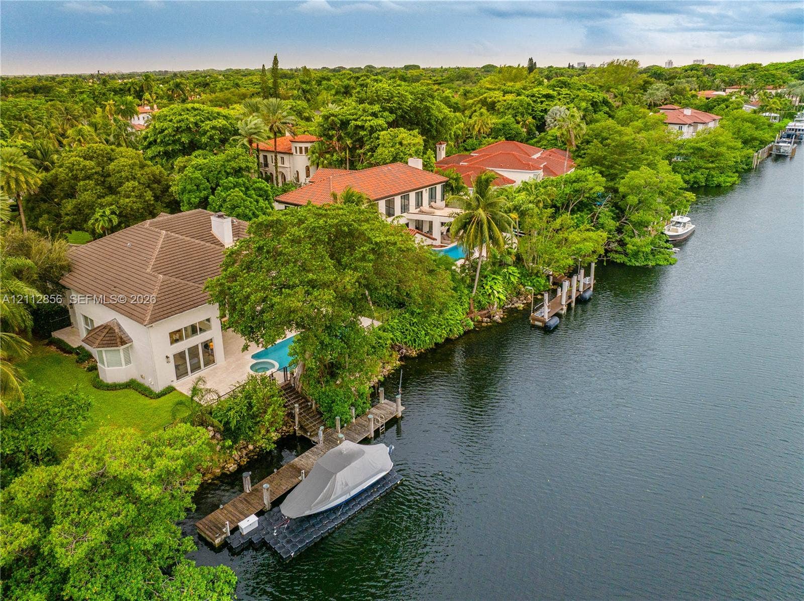 285 Las Brisas Court, Coral Gables, FL 33143 Waterfront estate featuring a private boat dock, tile roofing, an inground pool, and mature landscaping