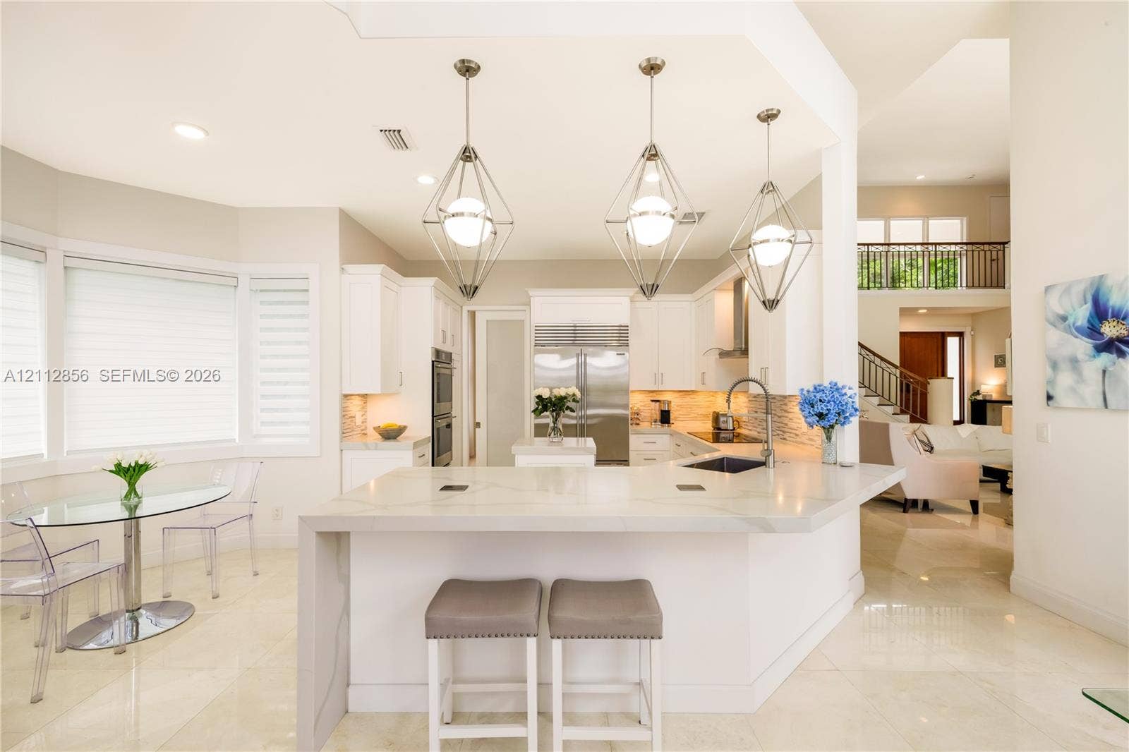 285 Las Brisas Court, Coral Gables, FL 33143 Kitchen featuring a waterfall-edge stone island, geometric pendant lighting, built-in double ovens, and professional-grade stainless steel refrigerator