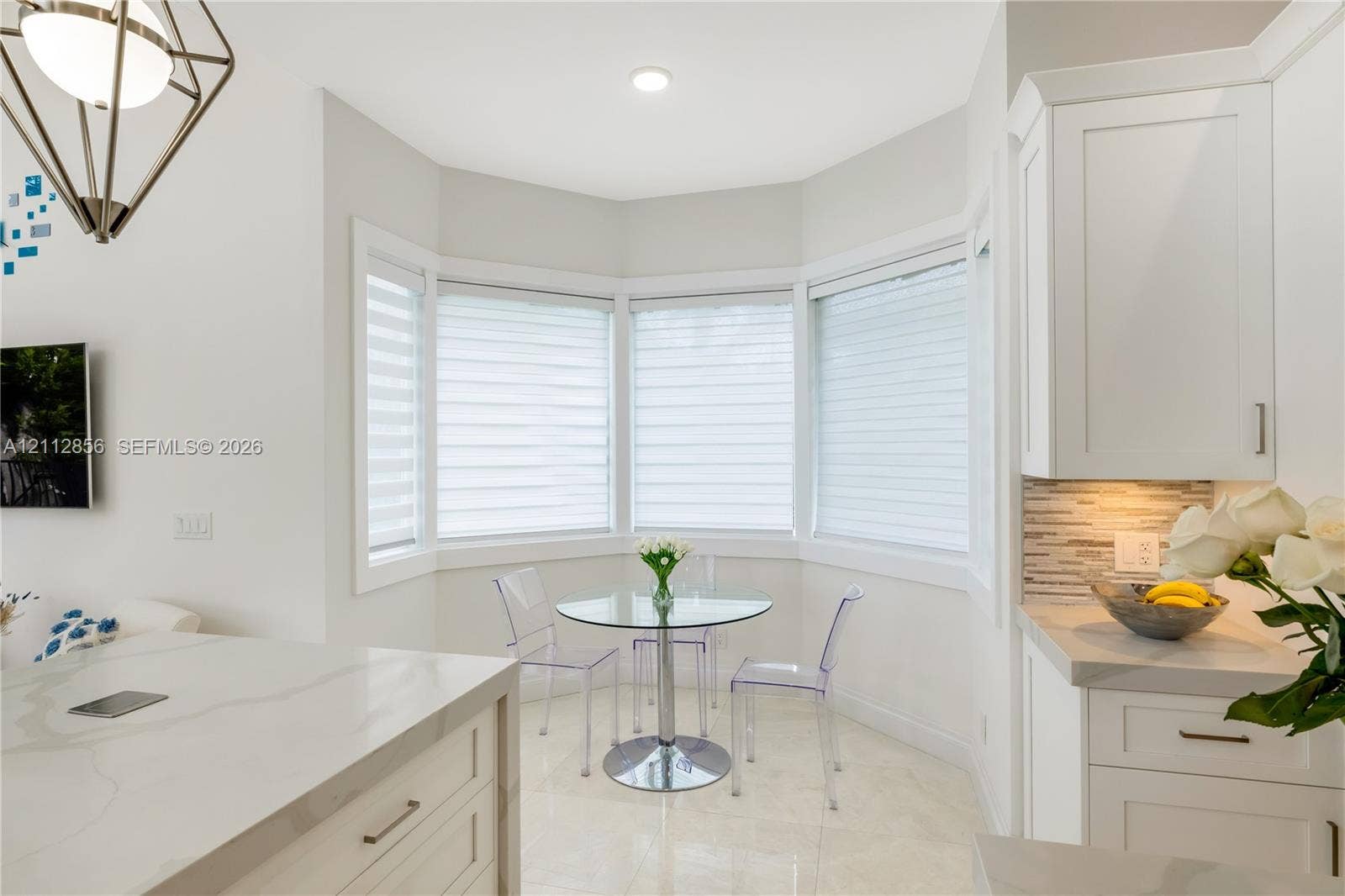 285 Las Brisas Court, Coral Gables, FL 33143 Kitchen nook featuring a bay window, white shaker-style cabinetry, stone-finish countertops, geometric metal pendant lighting, and neutral tile flooring