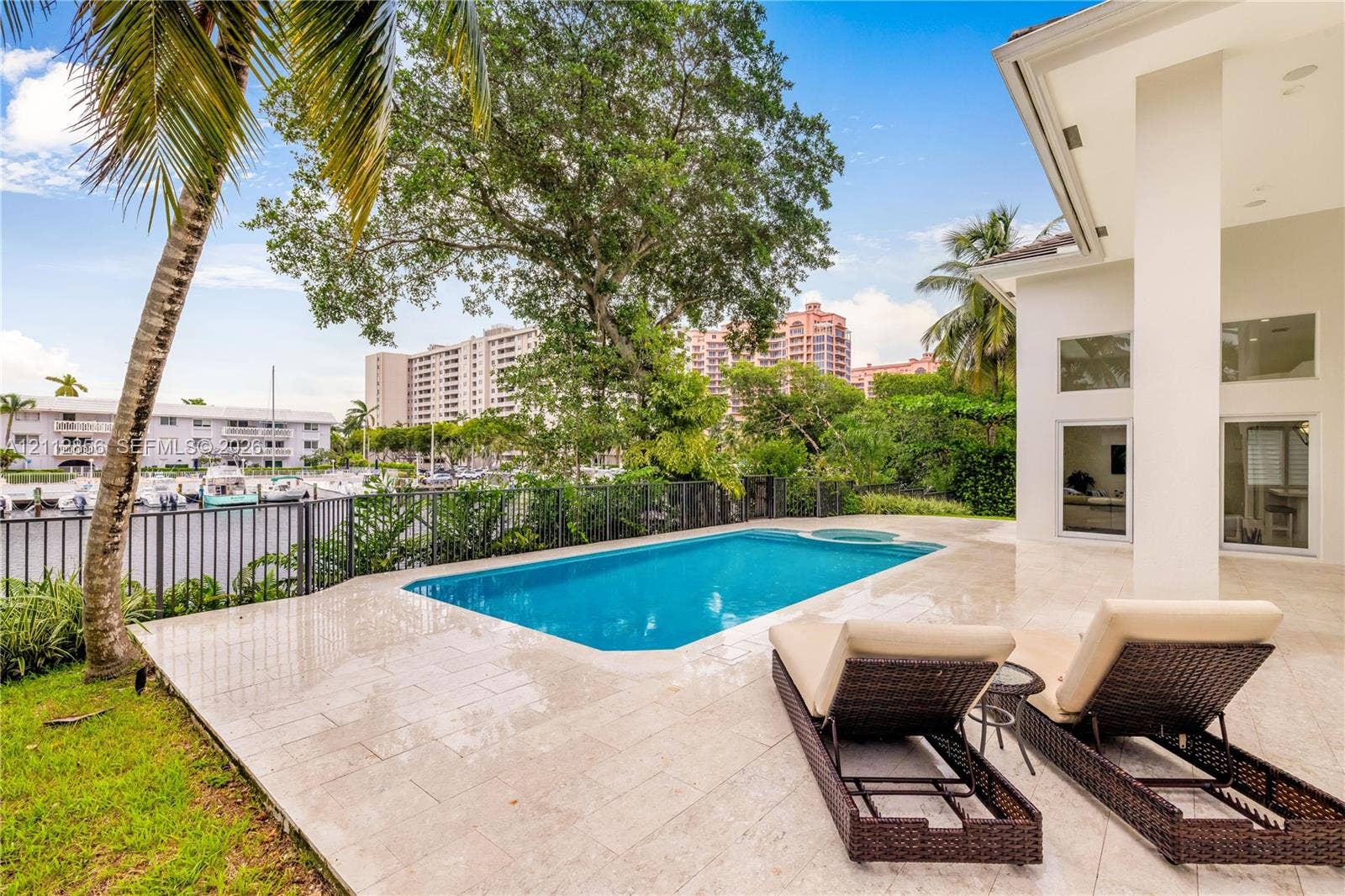 285 Las Brisas Court, Coral Gables, FL 33143 Outdoor terrace featuring natural stone tile flooring, a rectangular swimming pool with integrated spa, and a metal perimeter fence