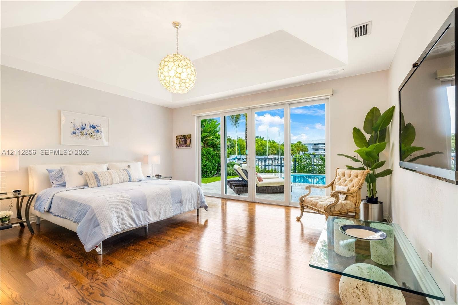285 Las Brisas Court, Coral Gables, FL 33143 Vaulted ceiling with decorative pendant lighting, wood-finish flooring, and expansive sliding glass doors providing outdoor access