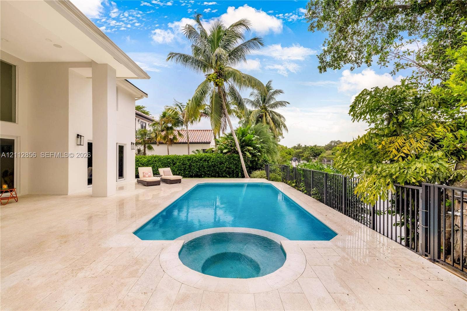285 Las Brisas Court, Coral Gables, FL 33143 Outdoor living space featuring a tiled pool deck, a swimming pool with an integrated spa, and metal perimeter fencing