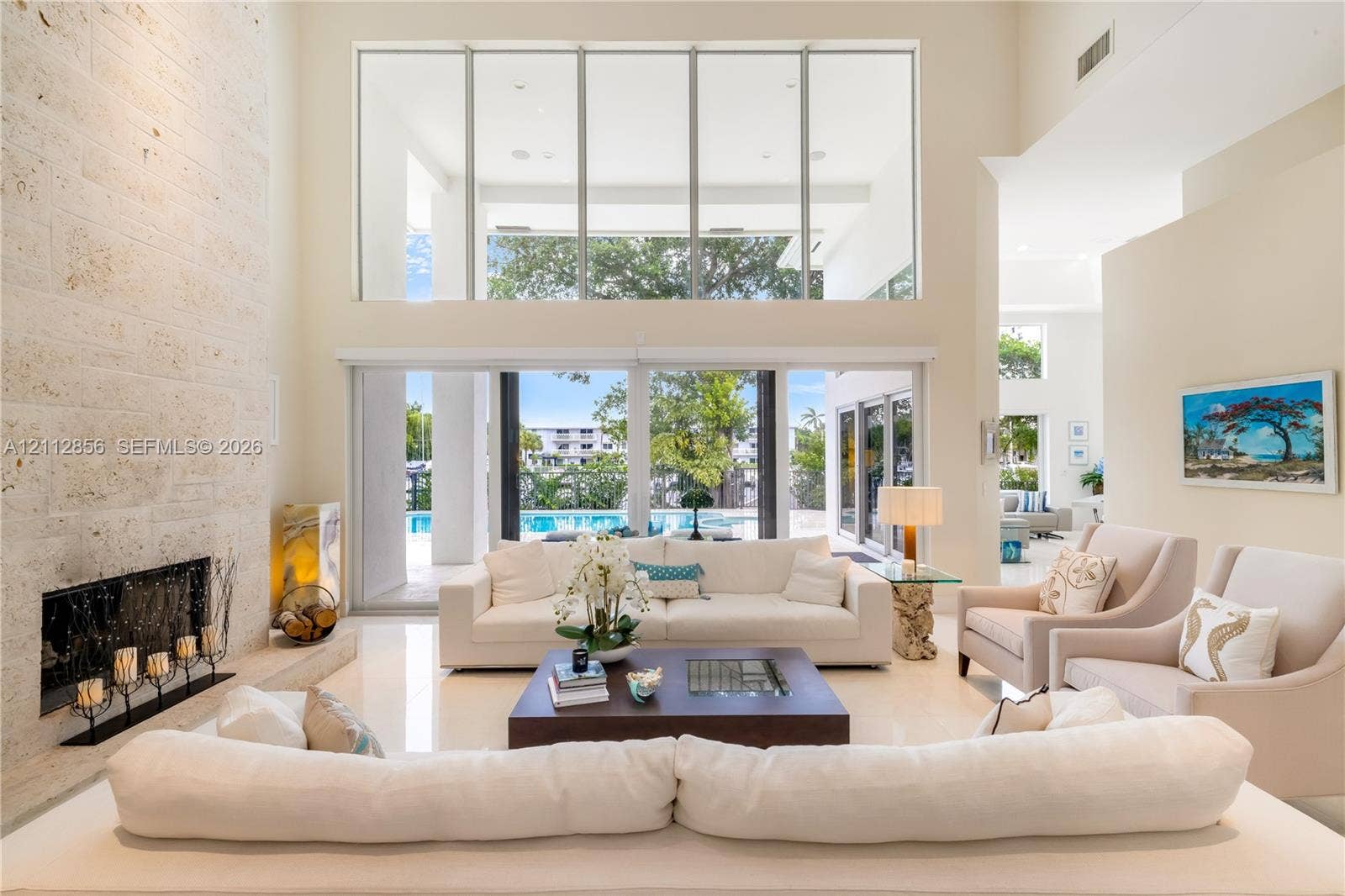285 Las Brisas Court, Coral Gables, FL 33143 Double-height living area featuring floor-to-ceiling windows, a full-height stone-clad fireplace, polished tile flooring, and sliding glass doors