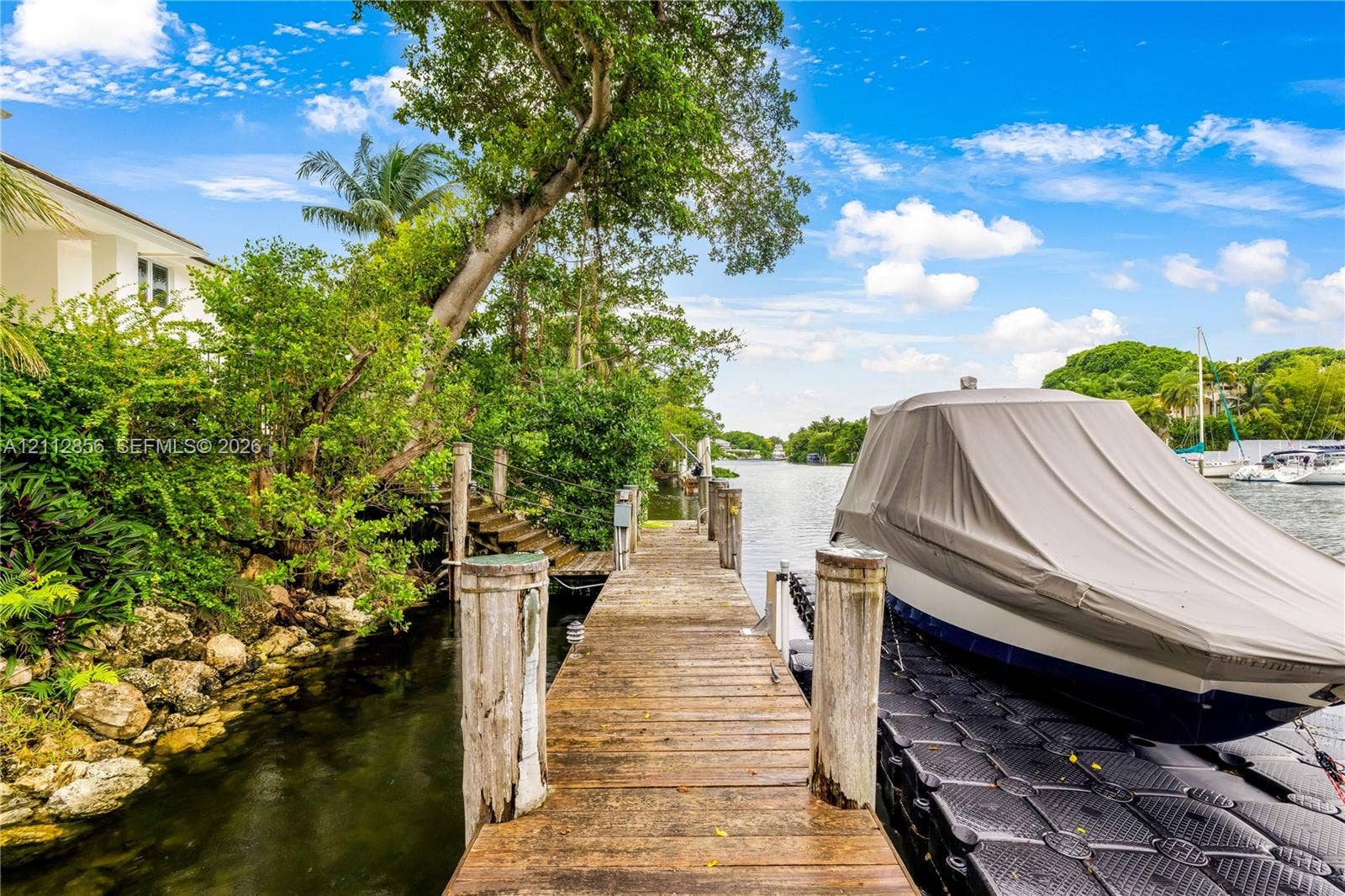 285 Las Brisas Court, Coral Gables, FL 33143 Waterfront dock featuring a wood-plank pier, stone-lined shoreline, and floating docking platform